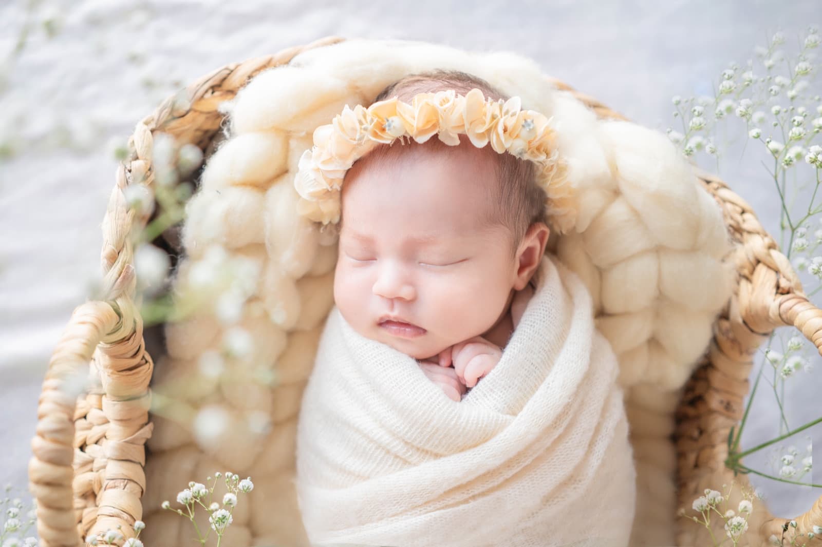 花冠をつけ、かごの中で眠る赤ちゃん